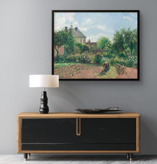 Framed painting of a garden scene above a wooden console table with a lamp and decorative plate.