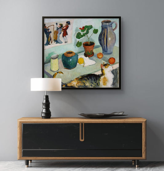 Framed painting of a still life scene with a cat on a wall above a wooden cabinet.