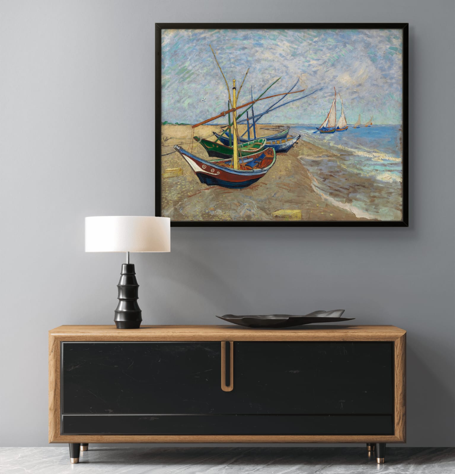 Framed painting of boats on a beach above a wooden console table with a lamp.