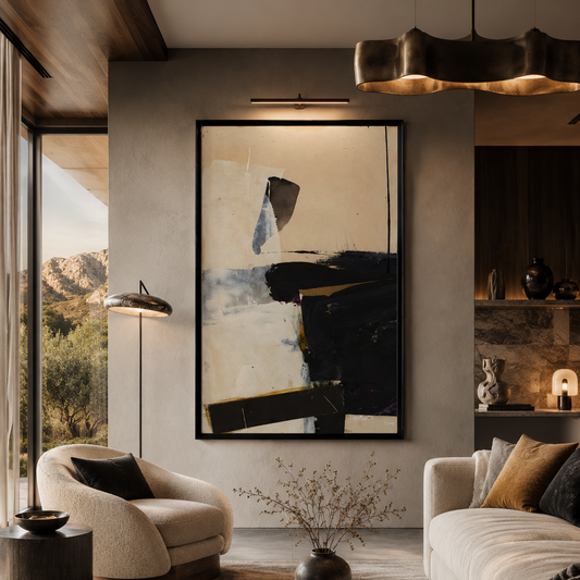A large framed abstract wall art print hangs in a modern living room setting. The artwork features bold black and beige brushstrokes with subtle gray accents, set in a black frame.