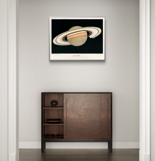 Framed artwork of Saturn on a wall above a wooden cabinet.
