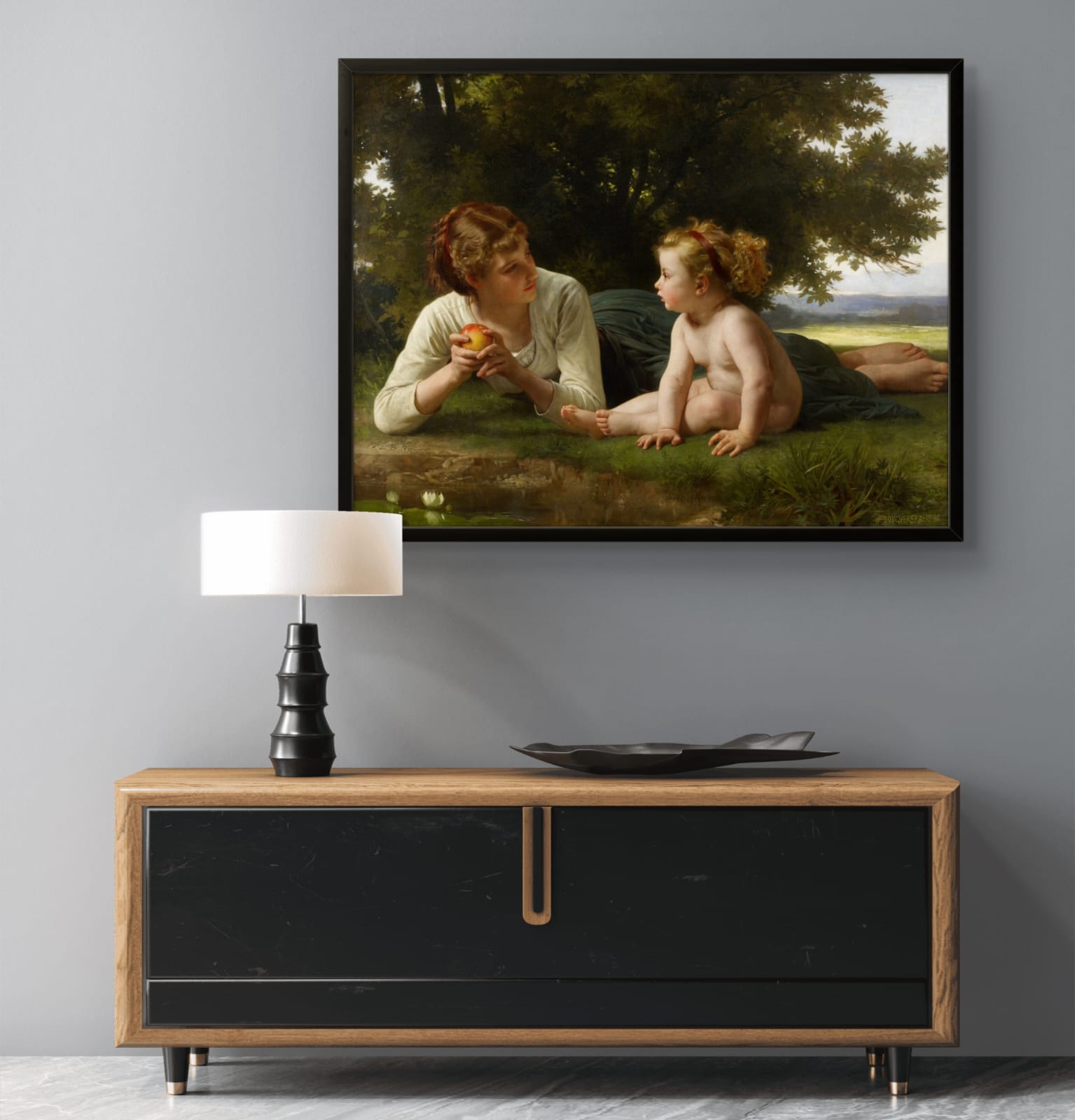 Framed painting of a woman and child by a lake above a wooden console table with a lamp.