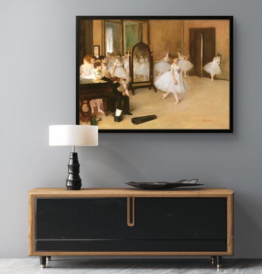 Framed painting of dancers in a room above a wooden console table with a lamp and decorative items.