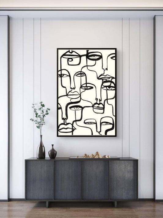 Abstract art piece of faces on a wall above a dark piece of furniture.